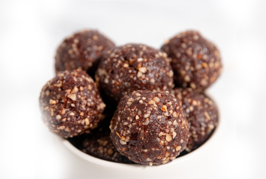 Gingerbread protein energy balls with hemp seeds, flaxseeds , almonds and walnuts in white bowl 