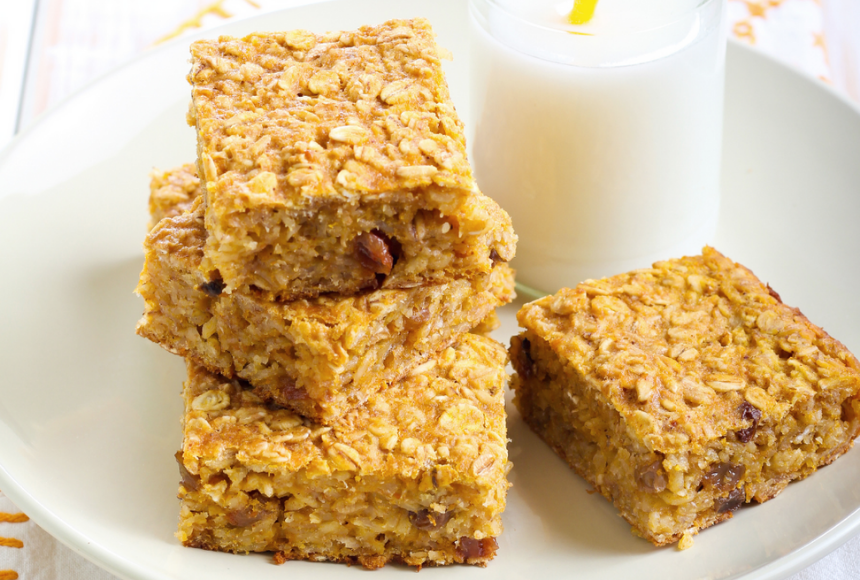 apple pie bars stacked on top of each other placed on a white plate with a tall glass of refreshing milk