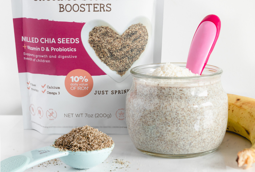 banana and chia seed pudding displayed in a small mason jar topped with fresh bananas and surrounded by scattered oatmeal flakes, bananas, and a small bowl of chia seeds