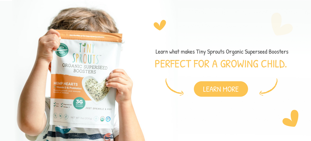 Toddler holding a bag of Tiny Sprouts Organic Hemp Heart Booster in front of his face. These products are great for the growing child.