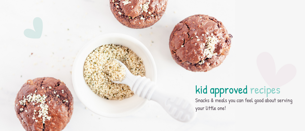 Chocolate protein hemp muffins displayed around a white bowl of hemp hearts with a white toddler spoon. 